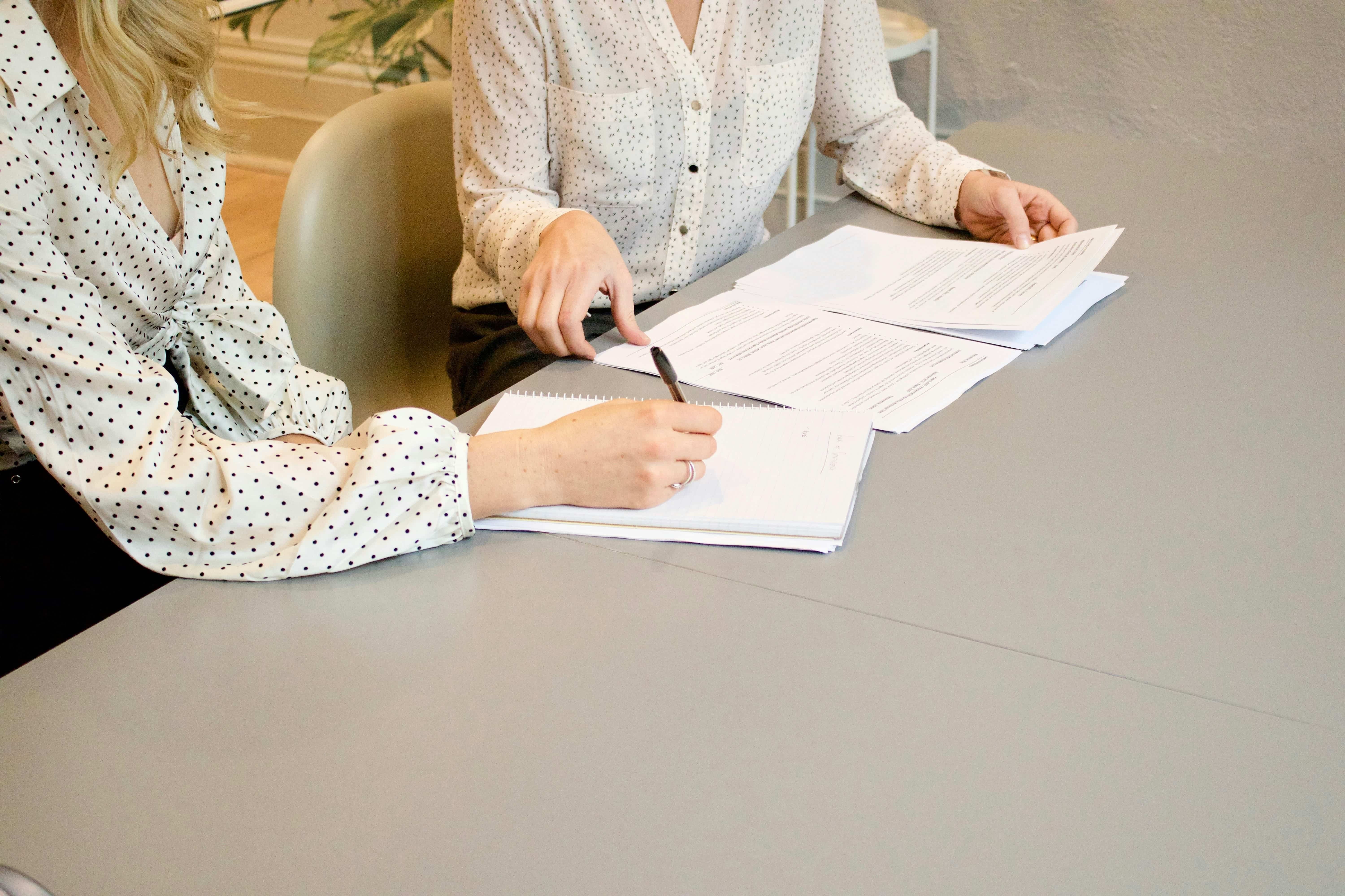 Co-workers writing on documents at a table